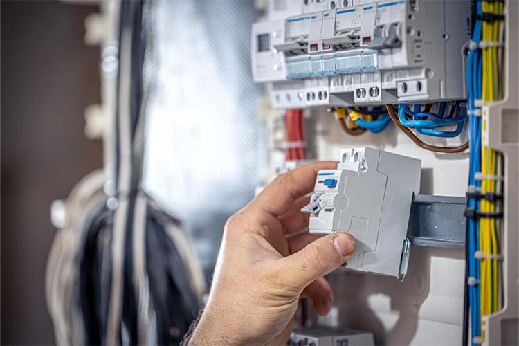 A hand fitting a breaker into an electrical panel