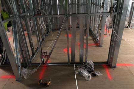 Steel stud framing with cables and red laser layout lines