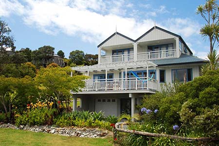 A pale two-storey house with balconies and a garden in front